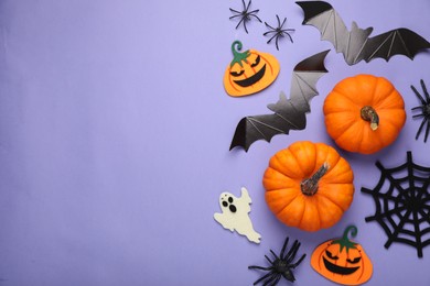 Photo of Flat lay composition with bats, pumpkins, ghost and spiders on purple background, space for text. Halloween celebration