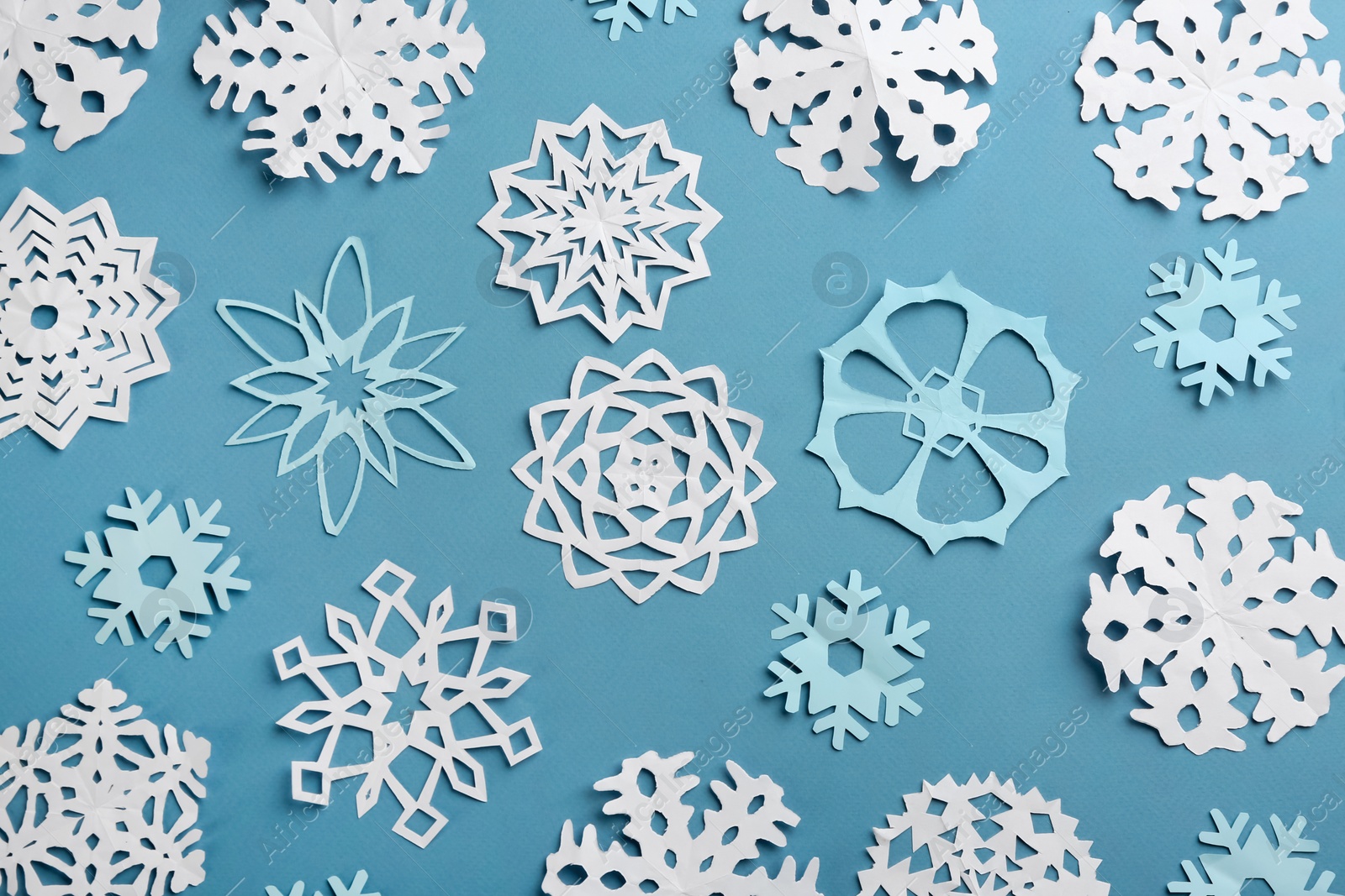 Photo of Many paper snowflakes on turquoise background, flat lay