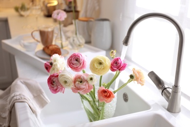 Beautiful fresh ranunculus flowers in kitchen sink