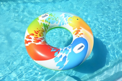 Colorful inflatable ring floating in swimming pool on sunny day, outdoors