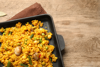 Photo of Delicious rice pilaf with vegetables on wooden table, top view