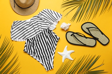 Photo of Flat lay composition with striped swimsuit and beach accessories on yellow background