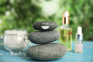 Stack of stones with drawn happy face light blue wooden table outdoors. Be in harmony and enjoying your life