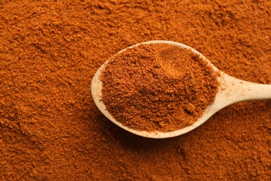 Photo of Closeup of wooden spoon with ground red pepper, top view