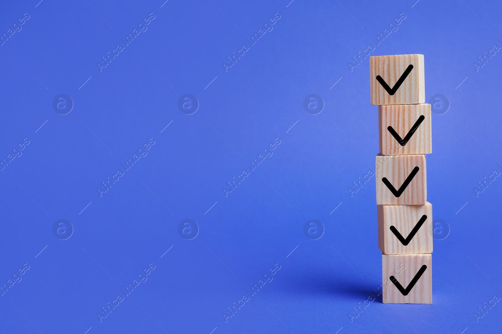 Image of Stacked wooden cubes with check marks on blue background. Space for text
