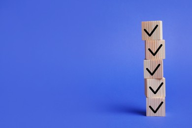 Image of Stacked wooden cubes with check marks on blue background. Space for text