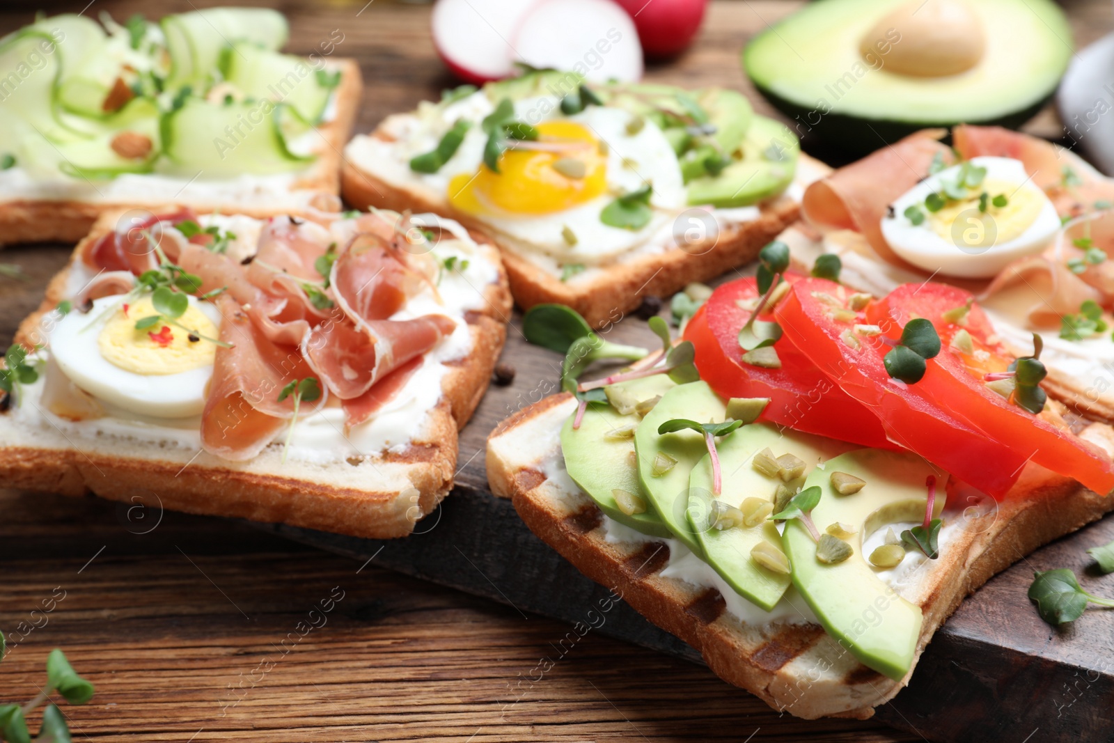 Photo of Different delicious sandwiches with microgreens on wooden board