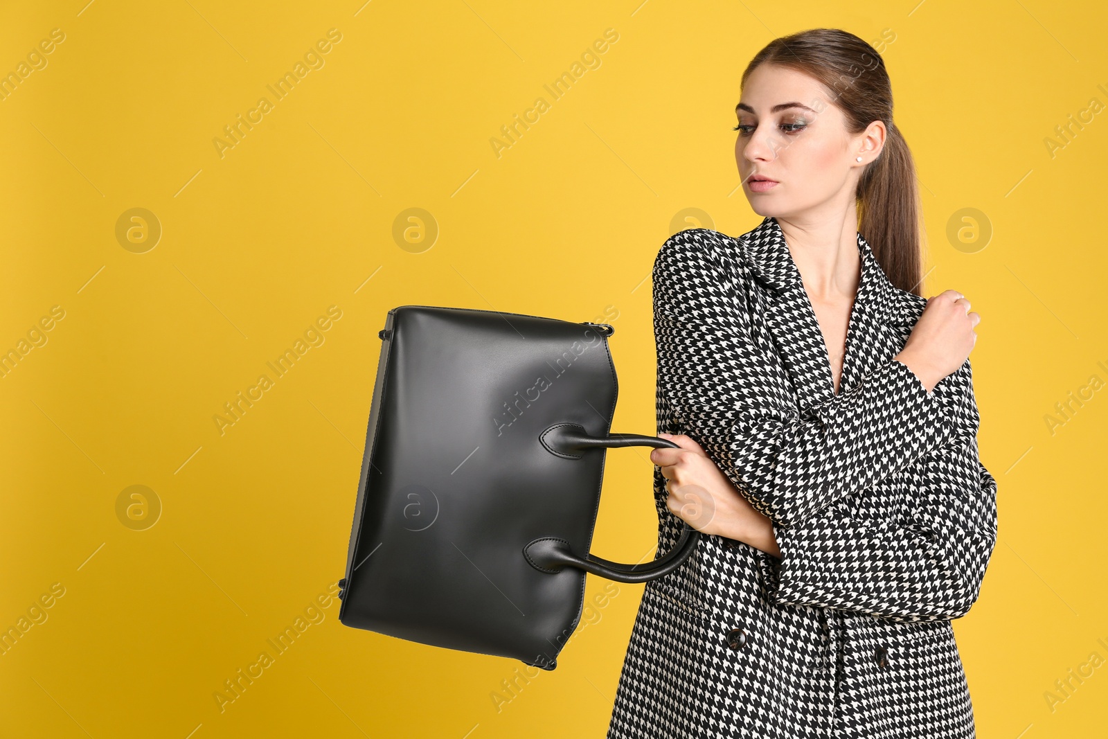 Photo of Beautiful young woman with stylish bag on yellow background