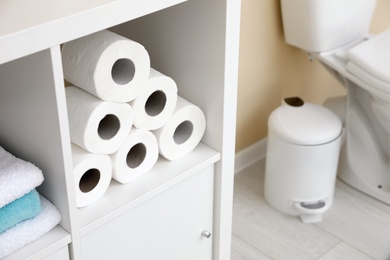Toilet paper rolls on cabinet shelf in bathroom