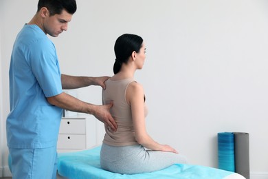 Orthopedist examining woman's back in clinic, space for text. Scoliosis treatment