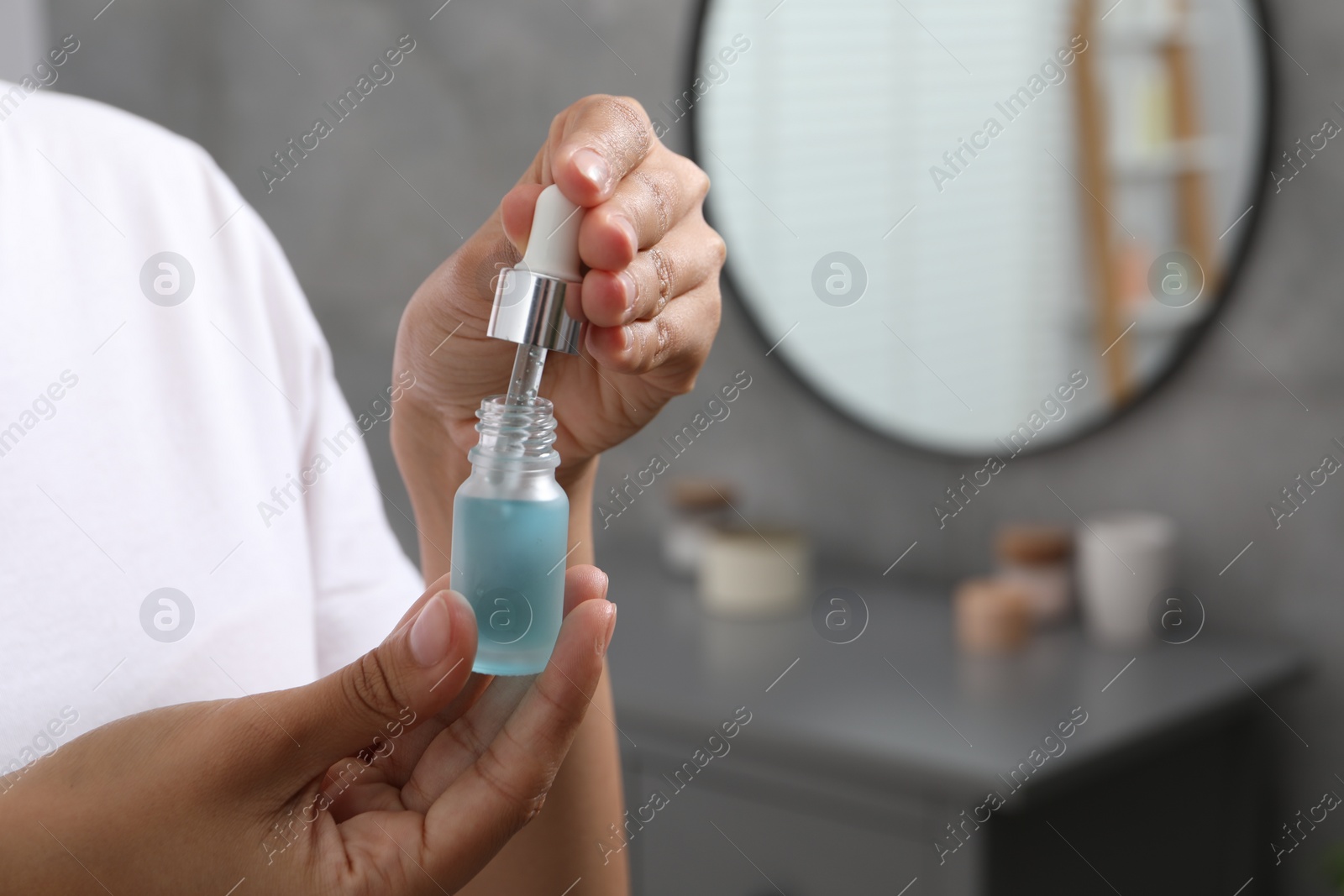 Photo of Woman with bottle of cosmetic serum and dropper indoors, closeup. Space for text
