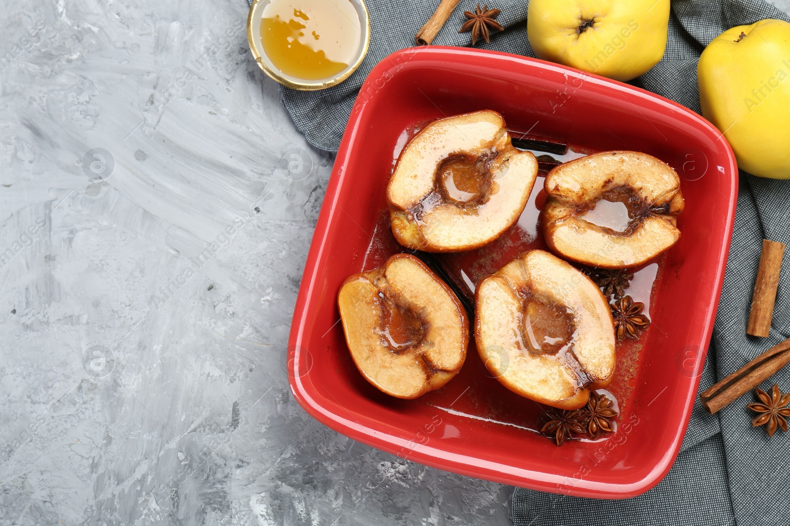 Photo of Tasty baked quinces with honey in dish on grey textured table, flat lay. Space for text