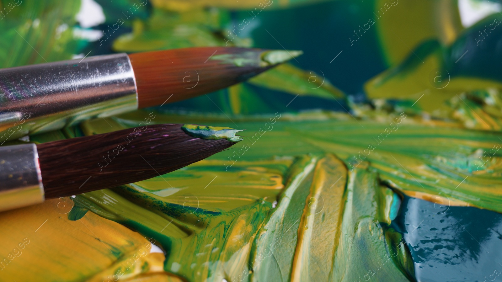 Photo of Brush on artist's palette with mixed paints, closeup