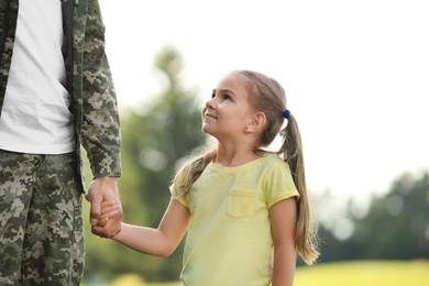 Photo of Little girl with her father in military uniform at sunny park