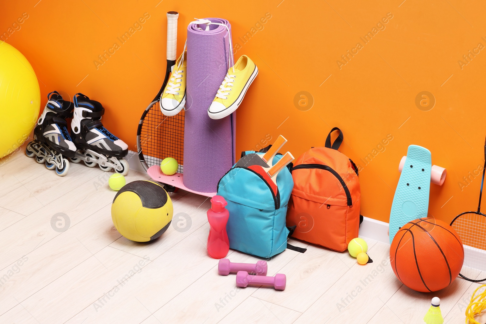 Photo of Many different sports equipment near orange wall indoors