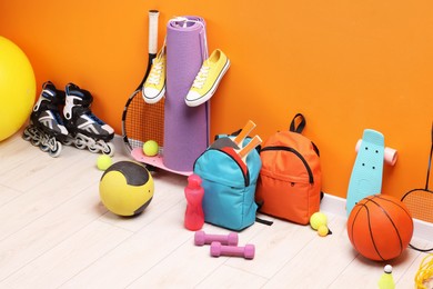 Photo of Many different sports equipment near orange wall indoors