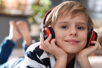 Cute little boy with headphones listening to audiobook at home