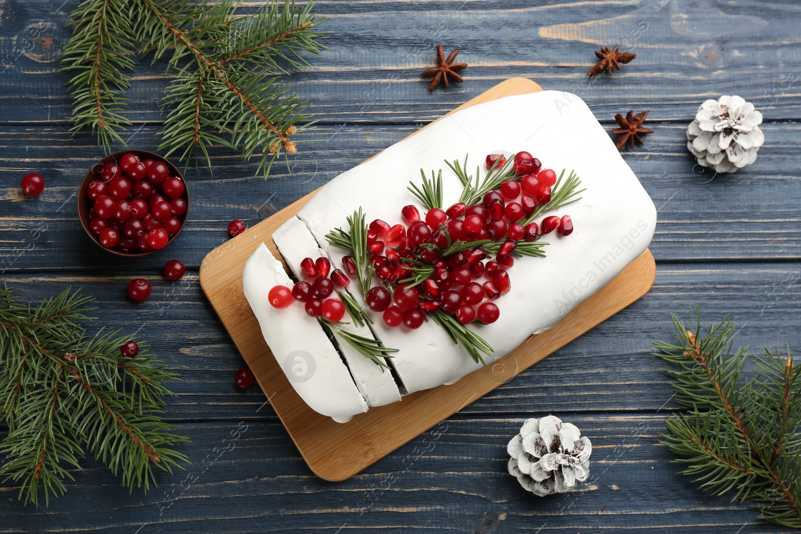 Photo of Flat lay composition with traditional classic Christmas cake with cranberries, pomegranate seeds and rosemary on blue wooden table