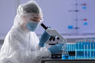 Scientist working with microscope and laboratory glassware at table