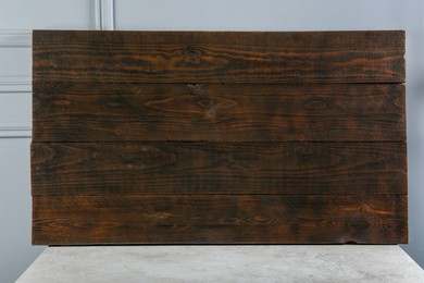 Dark wooden board on table near light grey wall