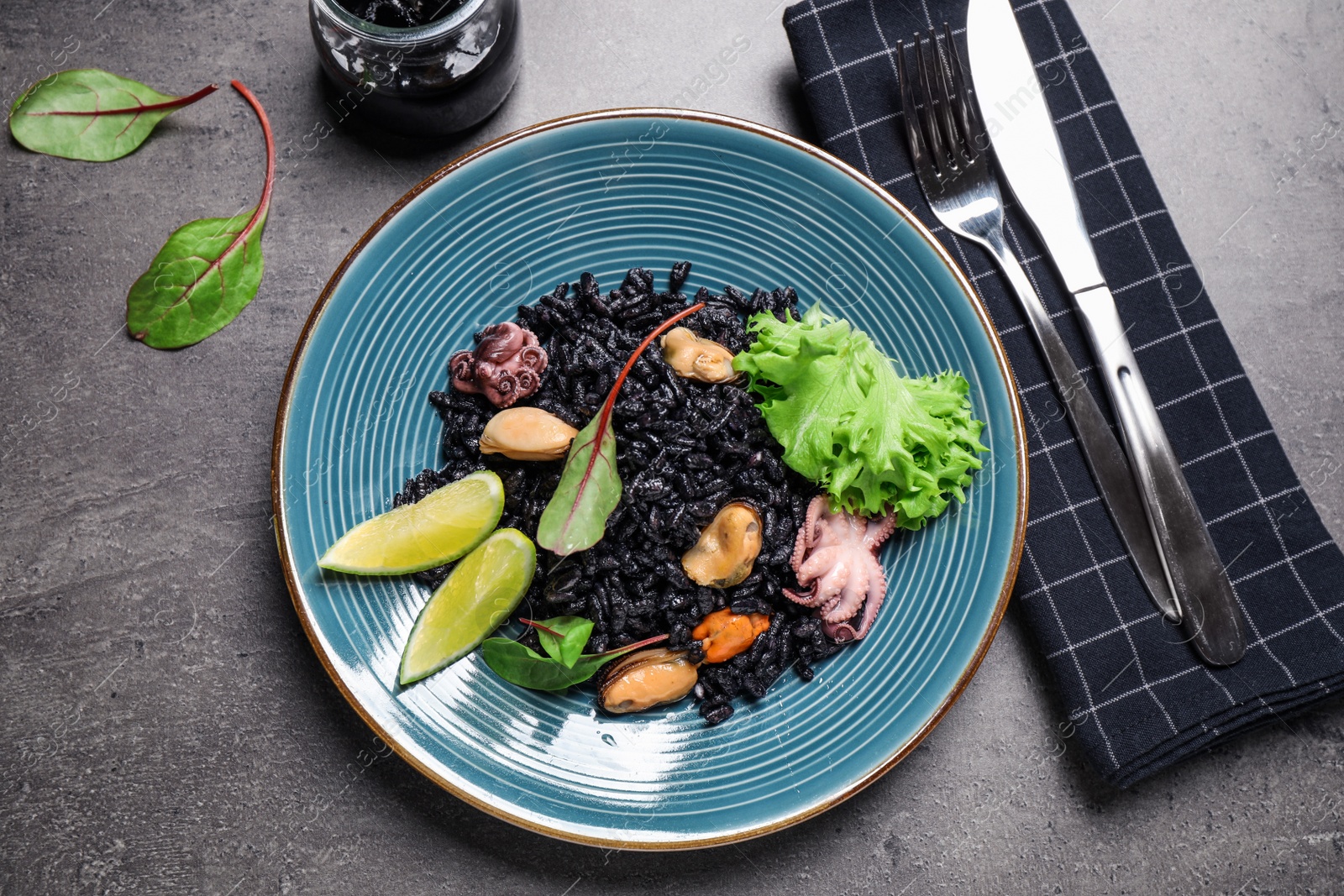 Photo of Delicious black risotto with seafood served on grey table