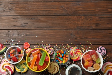 Photo of Flat lay composition with different yummy candies and space for text on wooden background