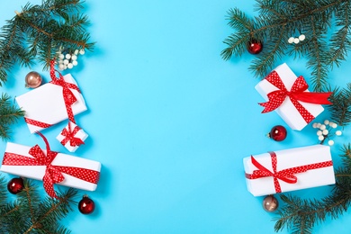 Gift boxes, fir branches and Christmas balls on light blue background, flat lay. Space for text