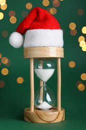 Hourglass and Santa hat on green background. Christmas countdown