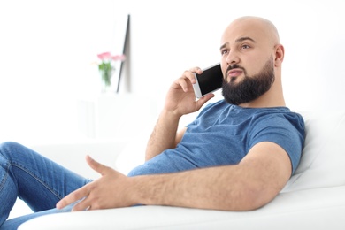 Photo of Portrait of young man talking on mobile phone on sofa