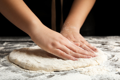 Woman kneading dough for pizza at grey table, closeup