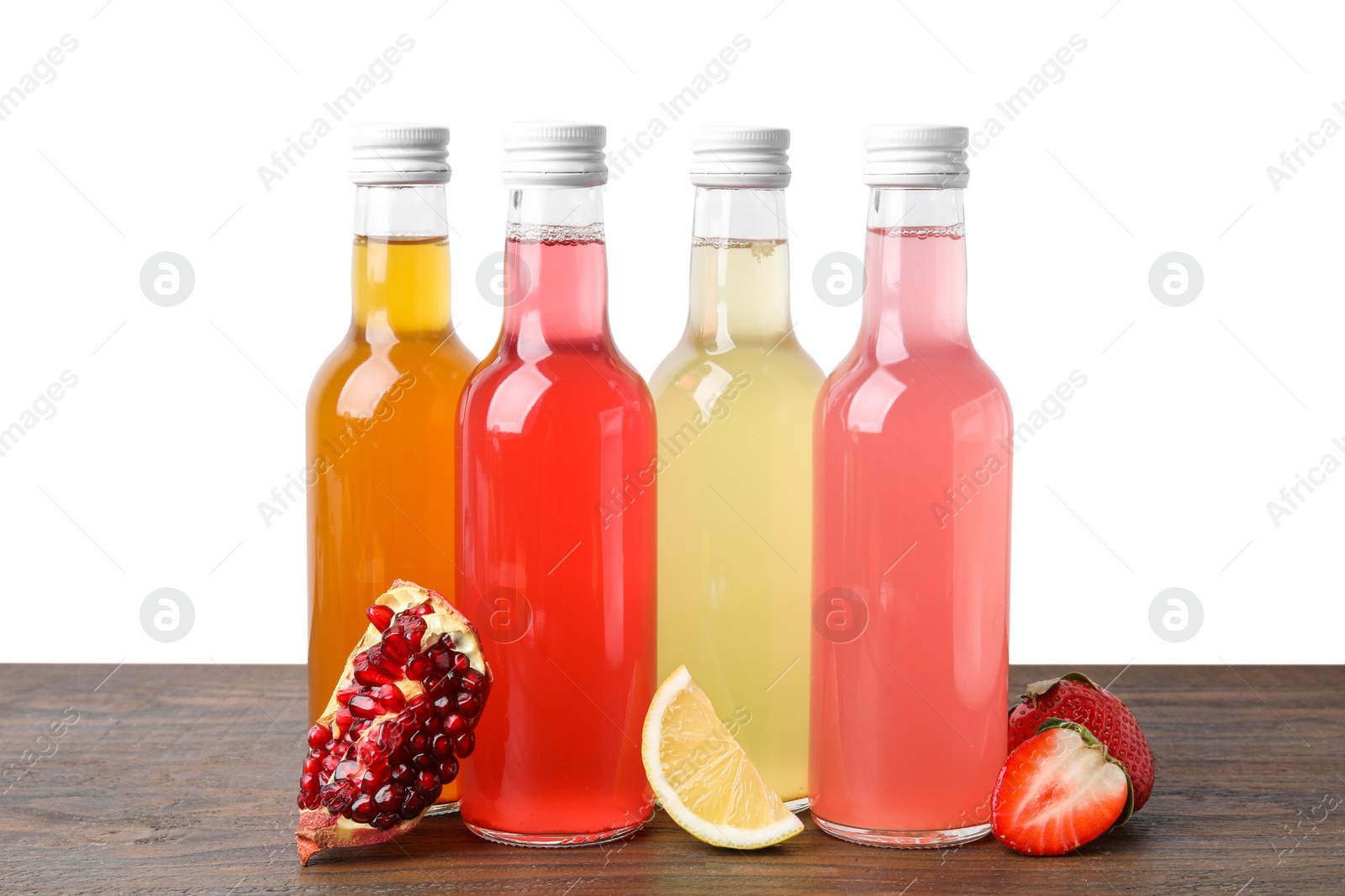 Photo of Delicious kombucha in glass bottles and fresh fruits on wooden table against white background