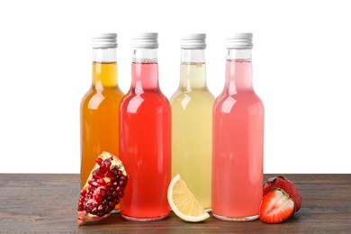 Photo of Delicious kombucha in glass bottles and fresh fruits on wooden table against white background