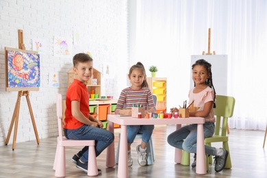 Photo of Cute little children drawing at painting lesson indoors