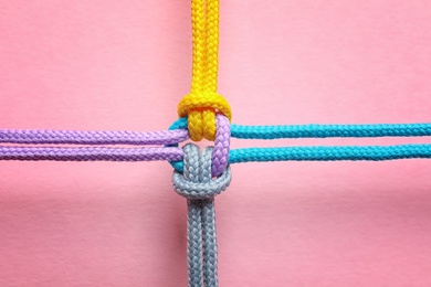Photo of Different ropes tied together with knot on color background. Unity concept