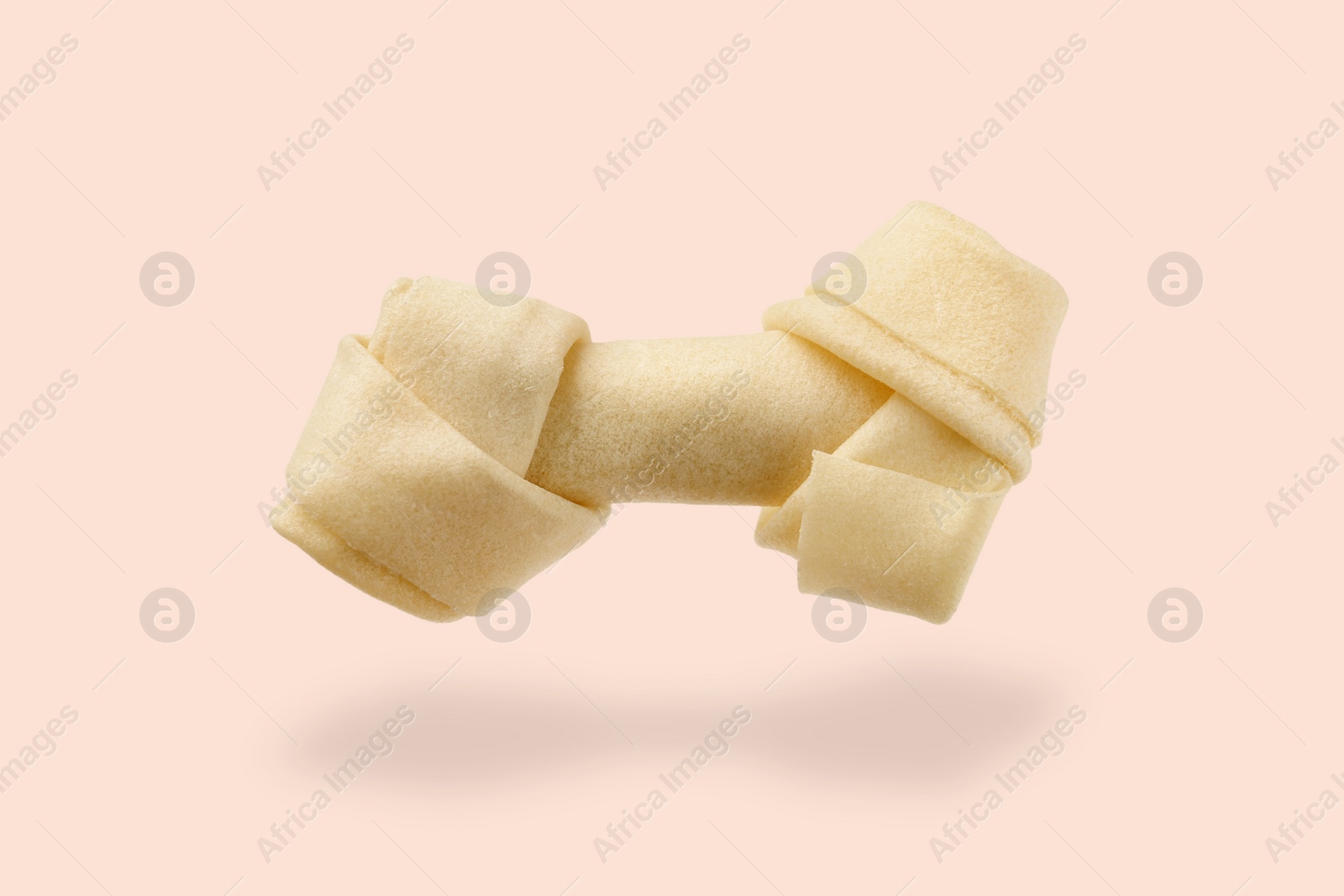 Image of Bone dog treat in air on beige pink background