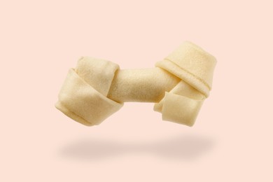 Bone dog treat in air on beige pink background