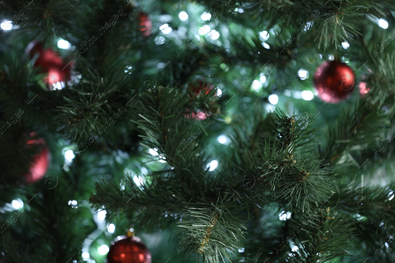 Photo of Christmas tree with bright string lights and ornaments, closeup. Bokeh effect