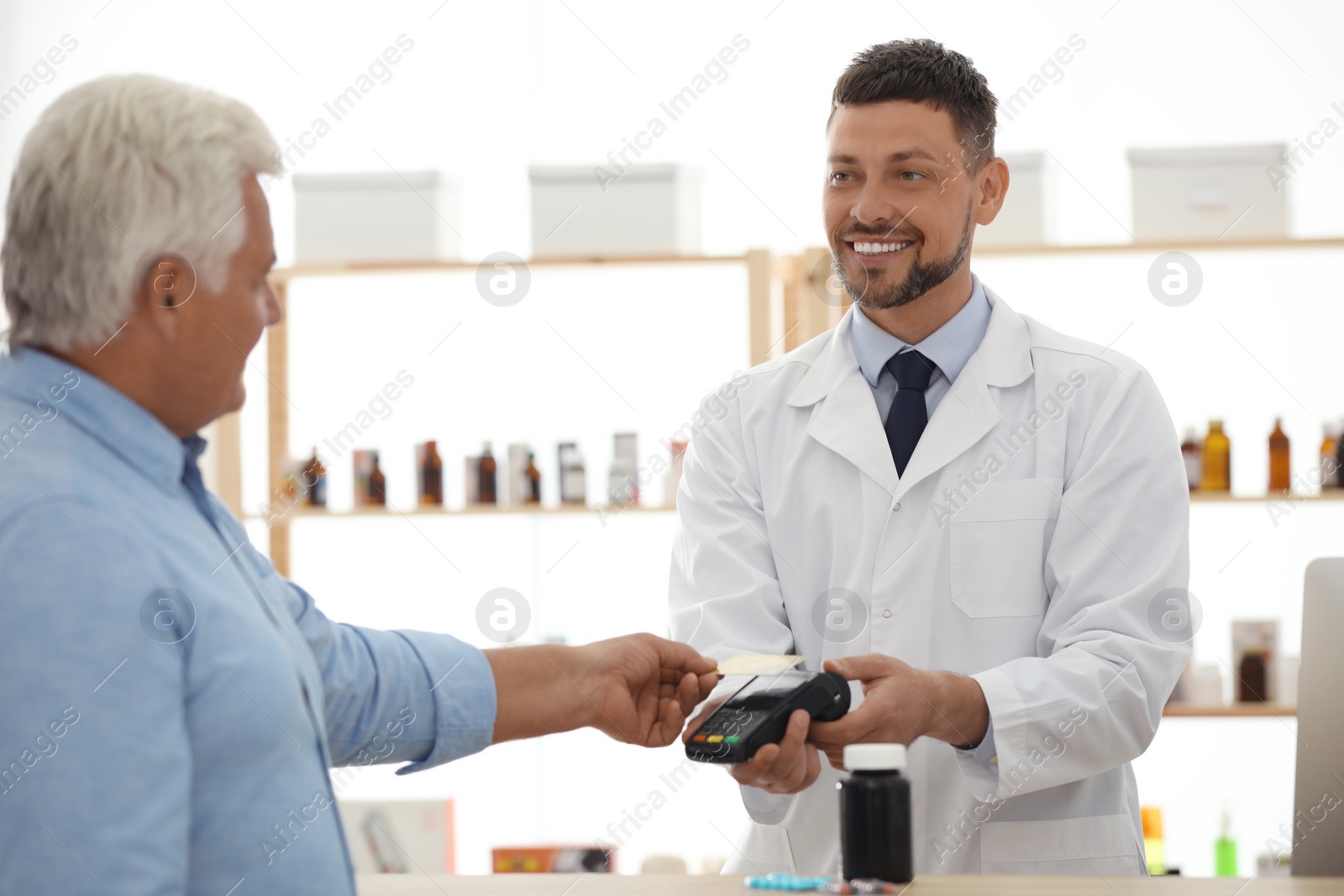 Photo of Customer using terminal for contactless payment with credit card in pharmacy