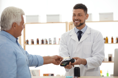 Photo of Customer using terminal for contactless payment with credit card in pharmacy