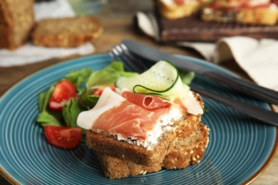 Plate of delicious bruschettas with prosciutto on table