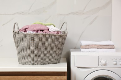 Photo of Wicker basket with dirty laundry on counter in bathroom