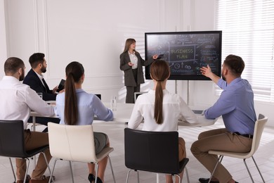 Photo of Business trainer using interactive board in meeting room during presentation