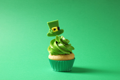 Photo of Delicious decorated cupcake on green background. St. Patrick's Day celebration