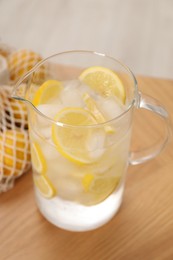 Photo of Freshly made lemonade in jug on wooden table indoors