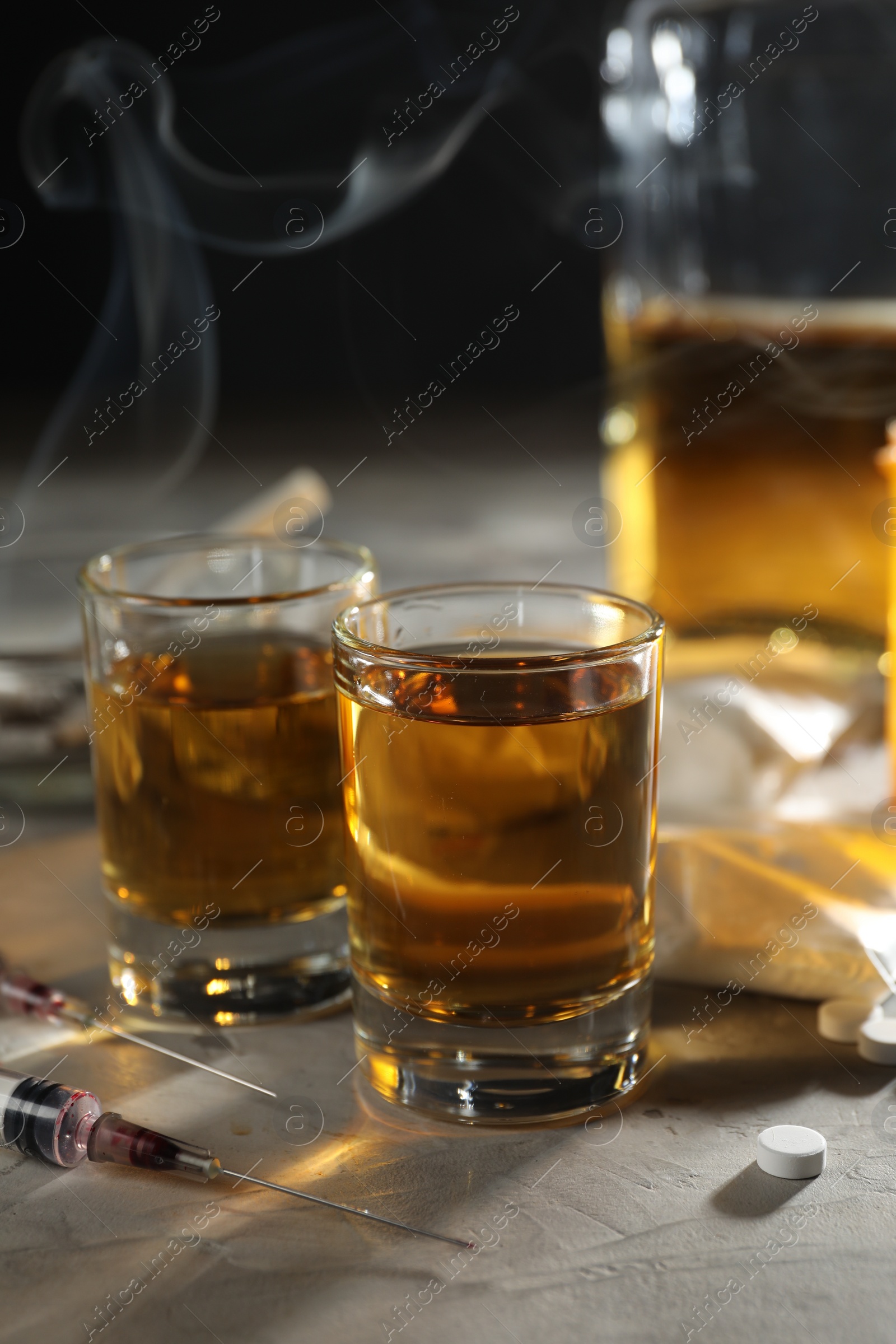 Photo of Alcohol and drug addiction. Whiskey in glasses, syringes and pills on grey background