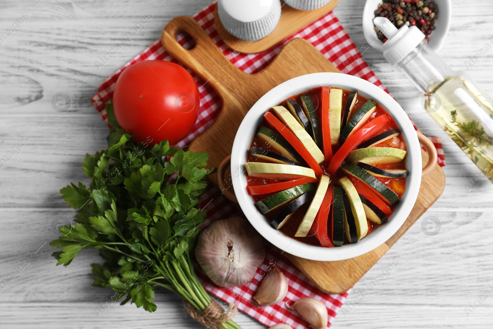Photo of Cooking delicious ratatouille. Dish with different vegetables on white wooden table, flat lay