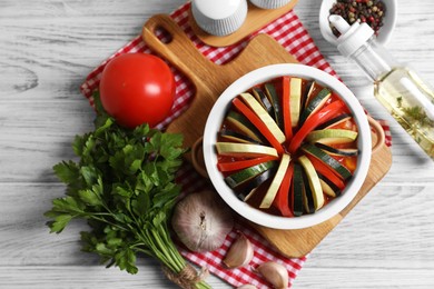 Photo of Cooking delicious ratatouille. Dish with different vegetables on white wooden table, flat lay