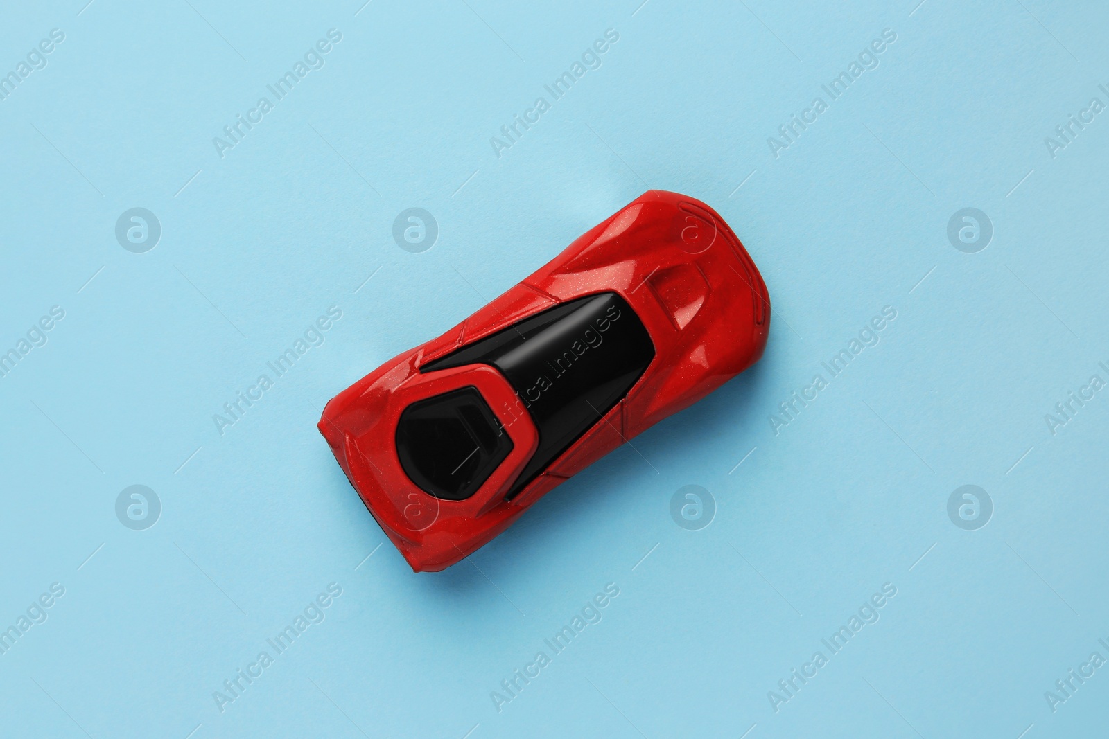 Photo of One red car on light blue background, top view. Children`s toy
