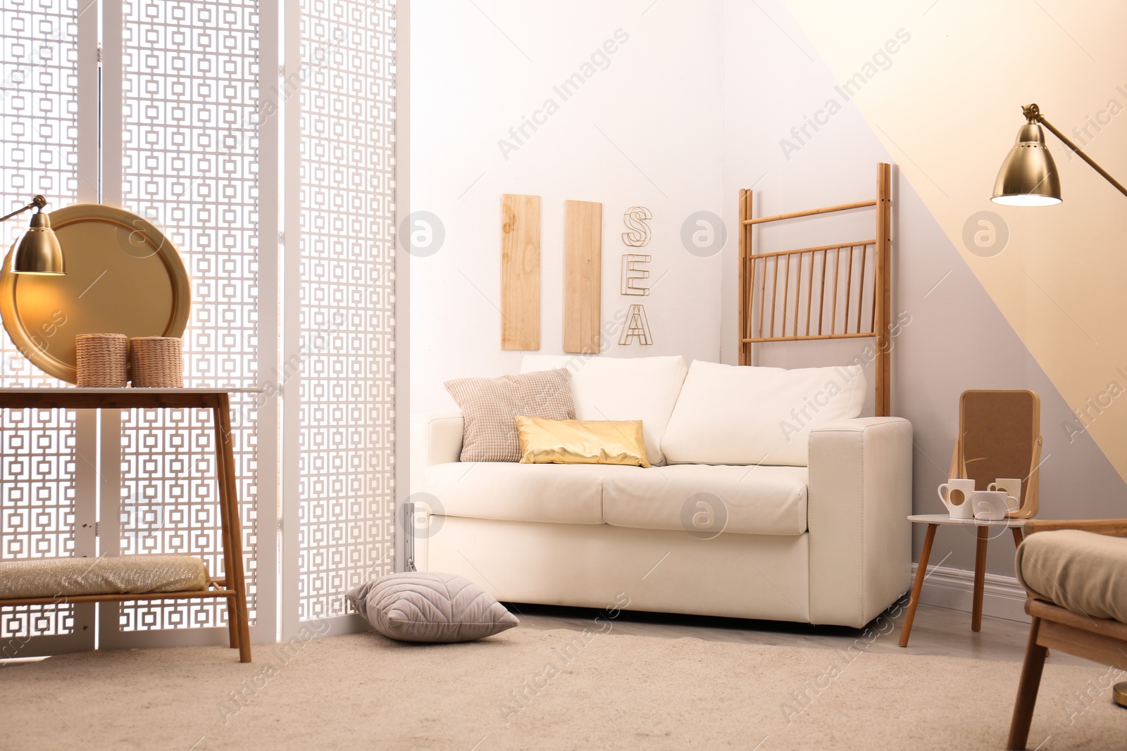 Photo of Stylish room interior with white folding screen and sofa