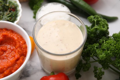 Photo of Different marinades in tableware on white table, closeup